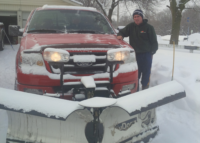 a man standing next to a truck with a snowplough attached
